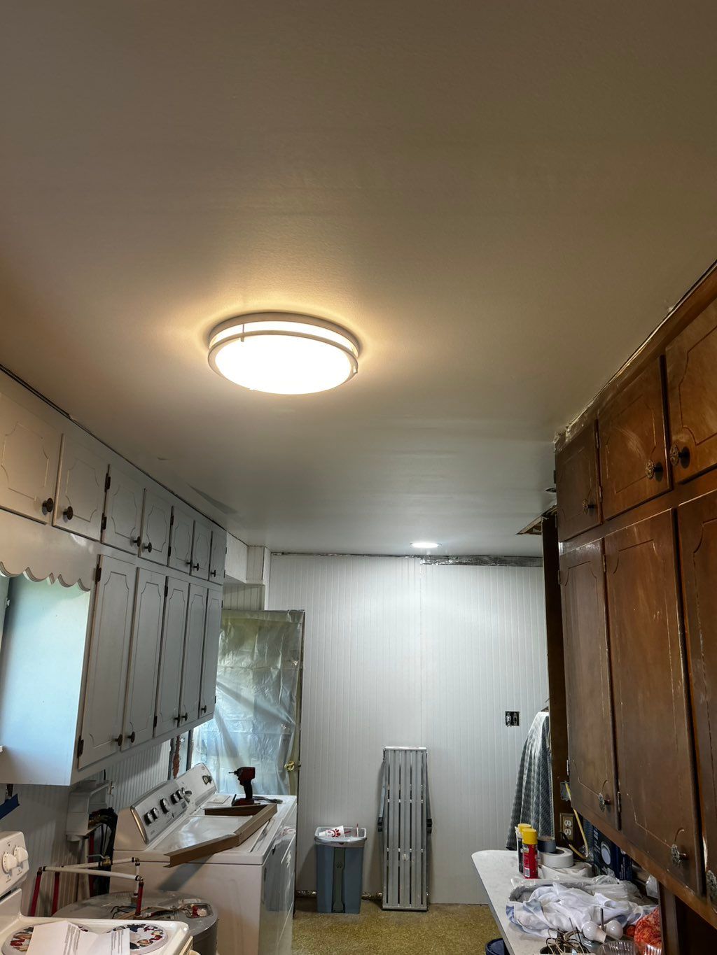 Kitchen with white cabinets, a lit ceiling fixture, and a white appliance.