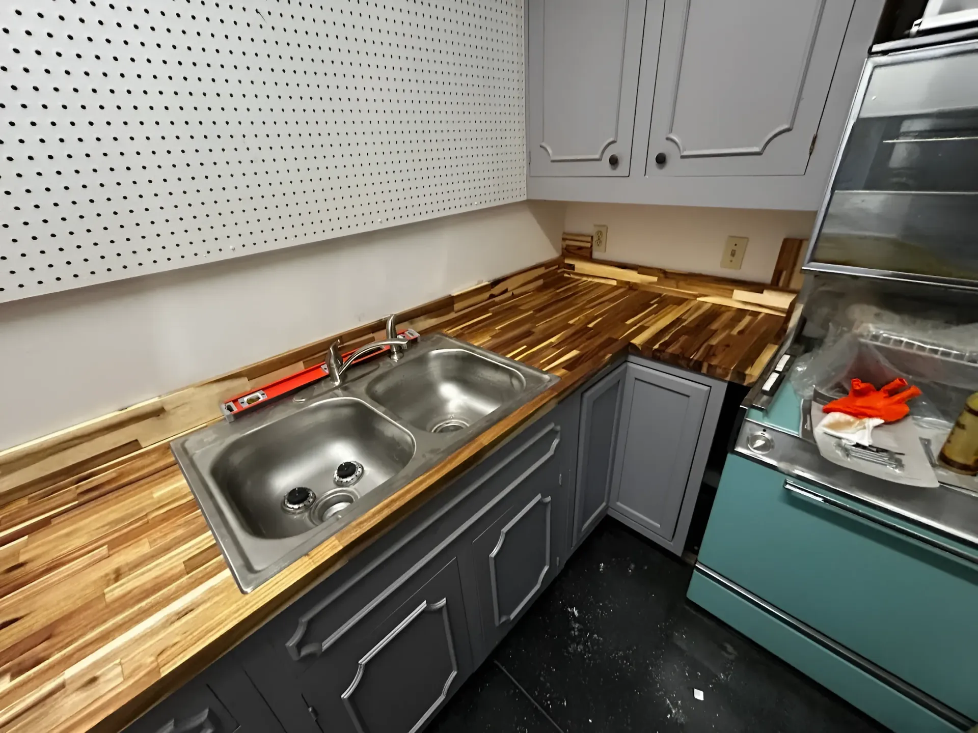 Gray kitchen cabinets with a butcher block countertop and a refrigerator.
