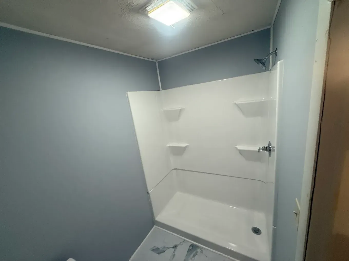 Small bathroom with blue walls and a white shower stall.