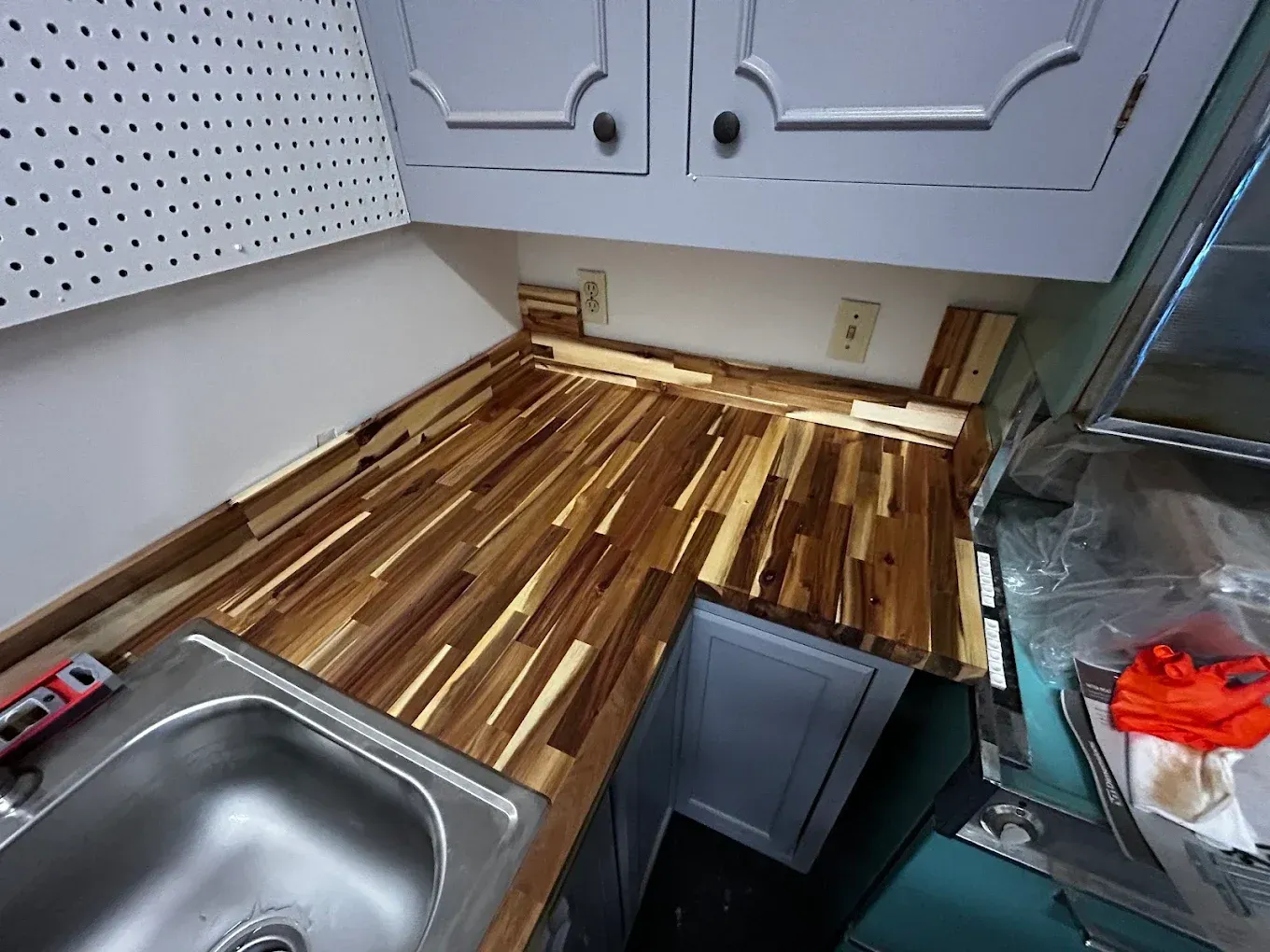Wooden butcher block countertop installation in a kitchen, with a sink and cabinets visible.