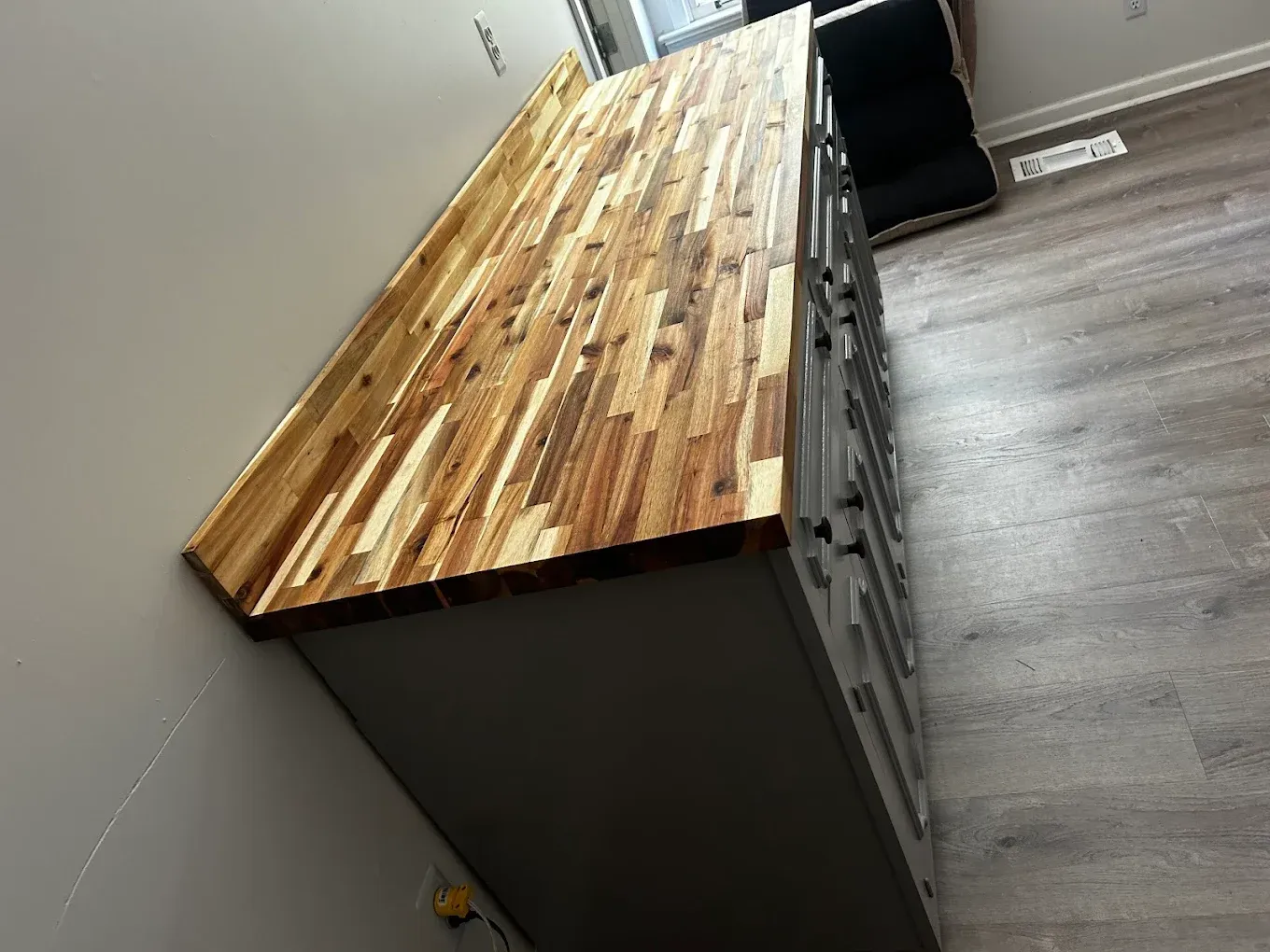 A long, gray cabinet with a wood butcher block countertop.