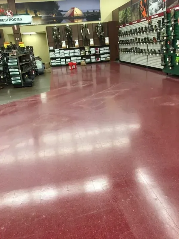 Red polished floor in a sporting goods store, with shelves of bows and other items.