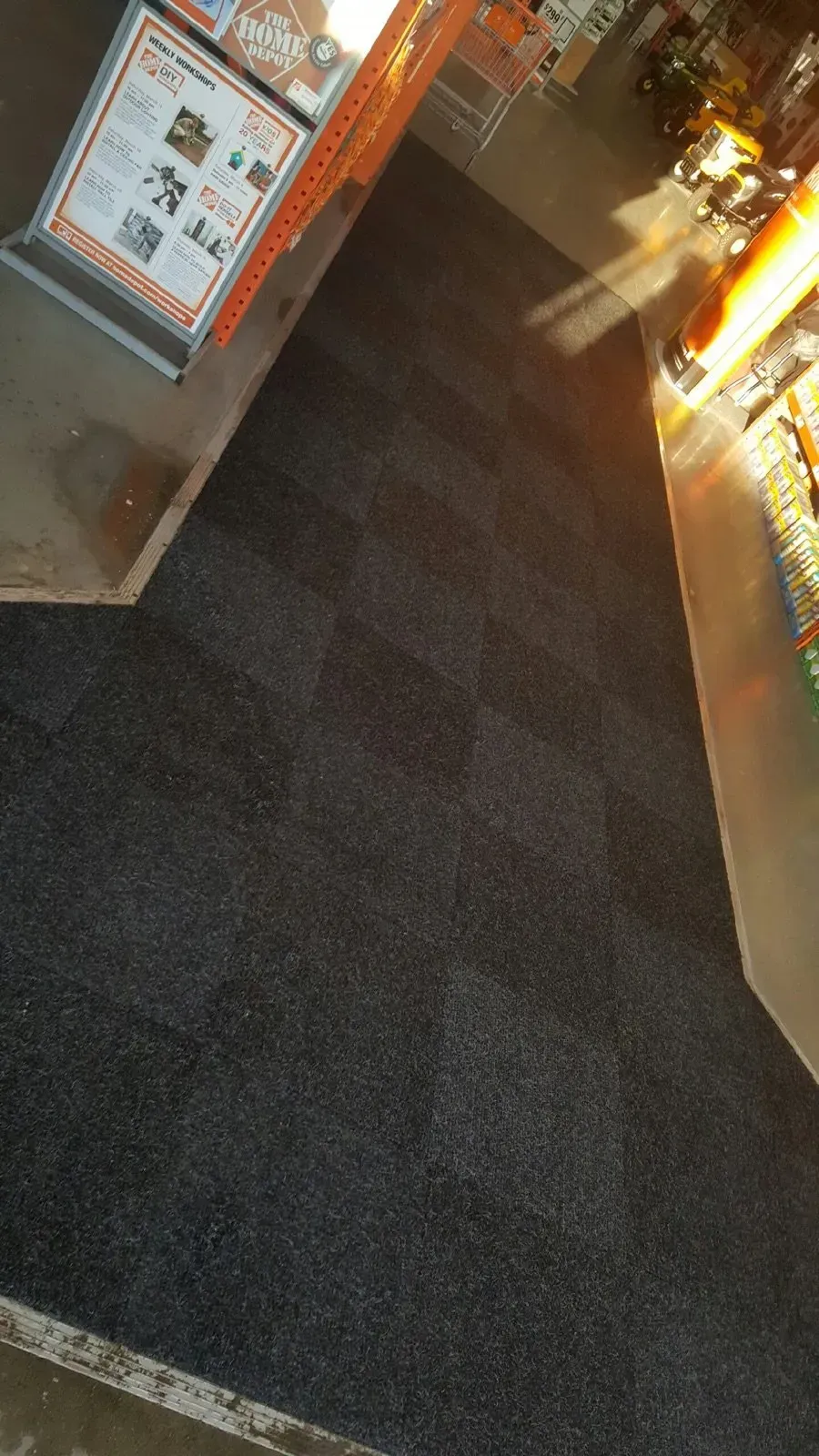 Dark gray carpeted floor in a store, with bright lighting and signage in view.