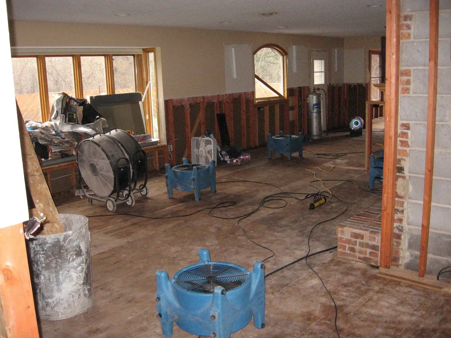 Basement with fans and dehumidifiers; water damage remediation in progress.