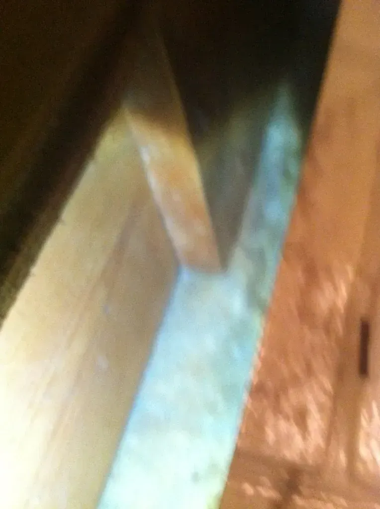 Close-up of wooden beams, illuminated. The beams meet at an angle, light reflects on their surfaces.