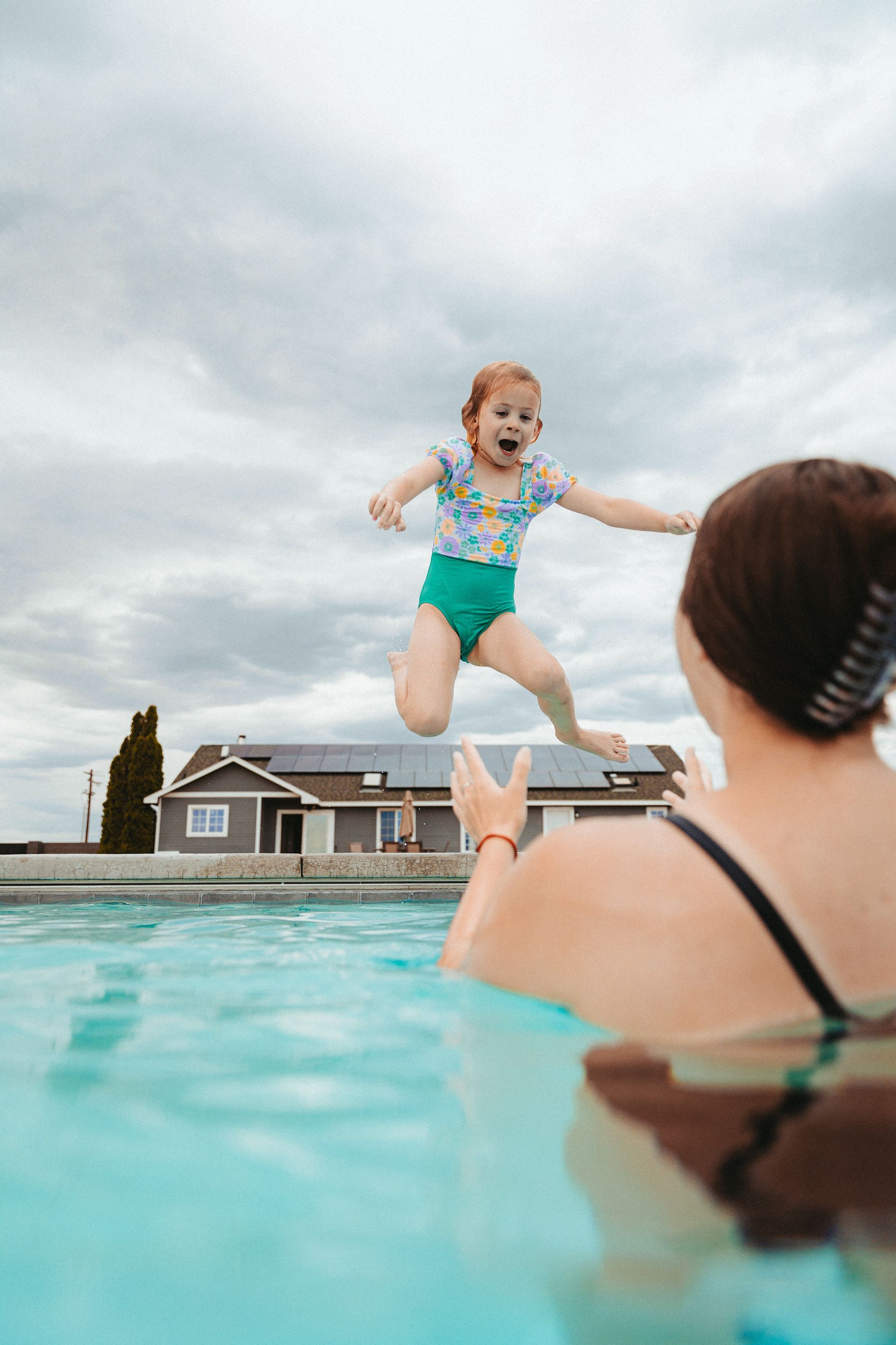 A little girl is jumping into a swimming pool.