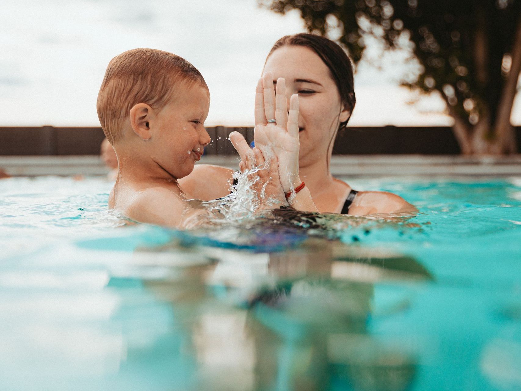 A woman is holding a baby in a swimming pool.