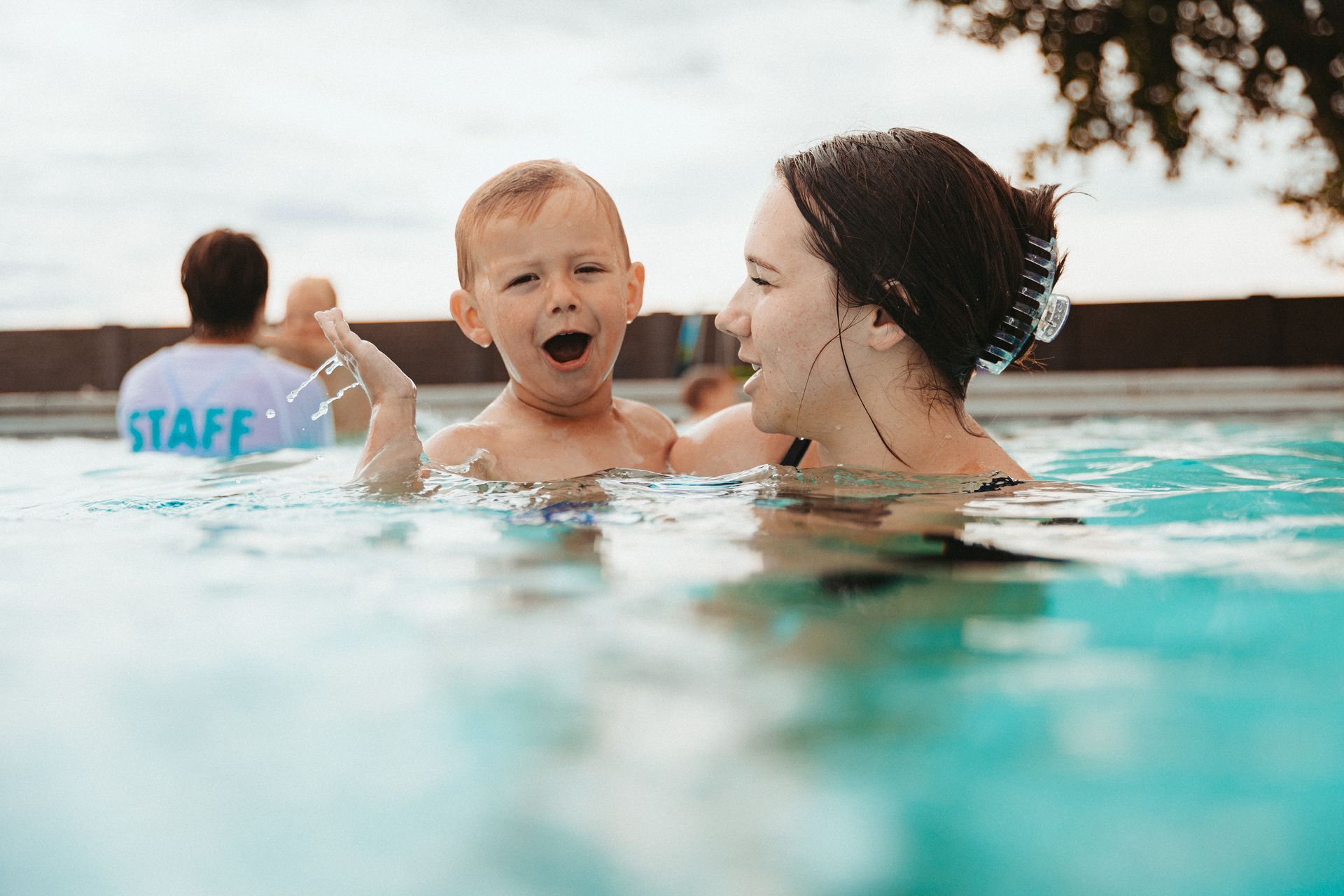 A woman is holding a baby in a swimming pool.