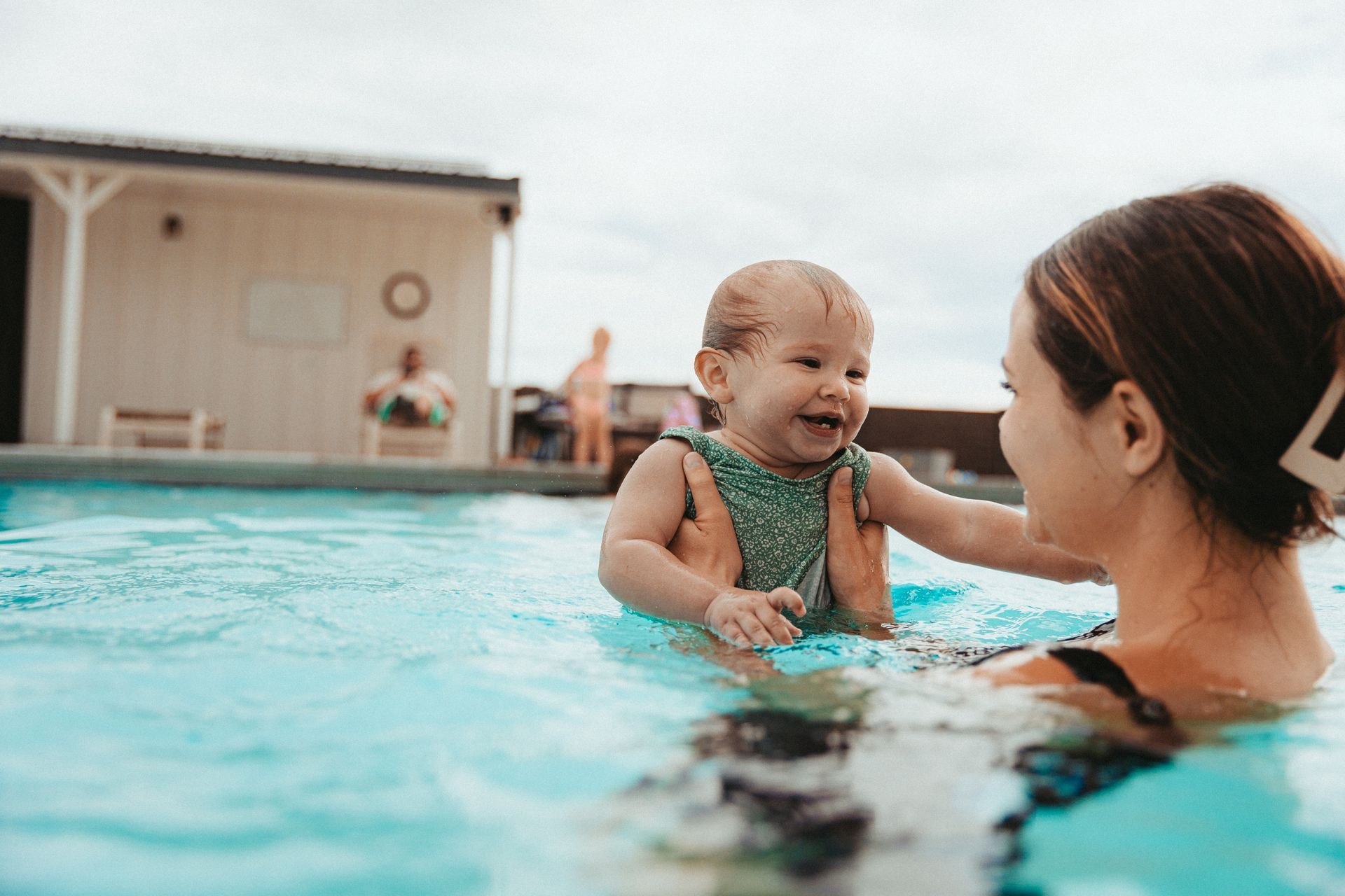 A woman is holding a baby in a swimming pool.