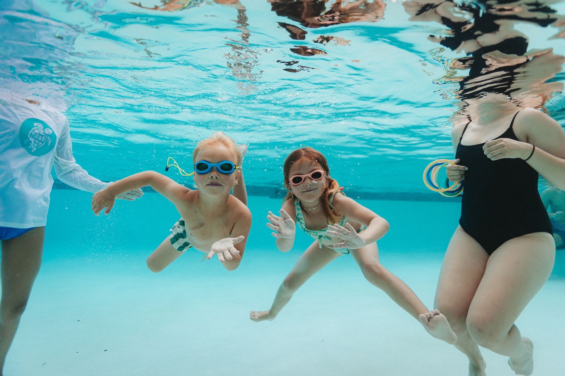 A group of children are swimming underwater in a swimming pool.