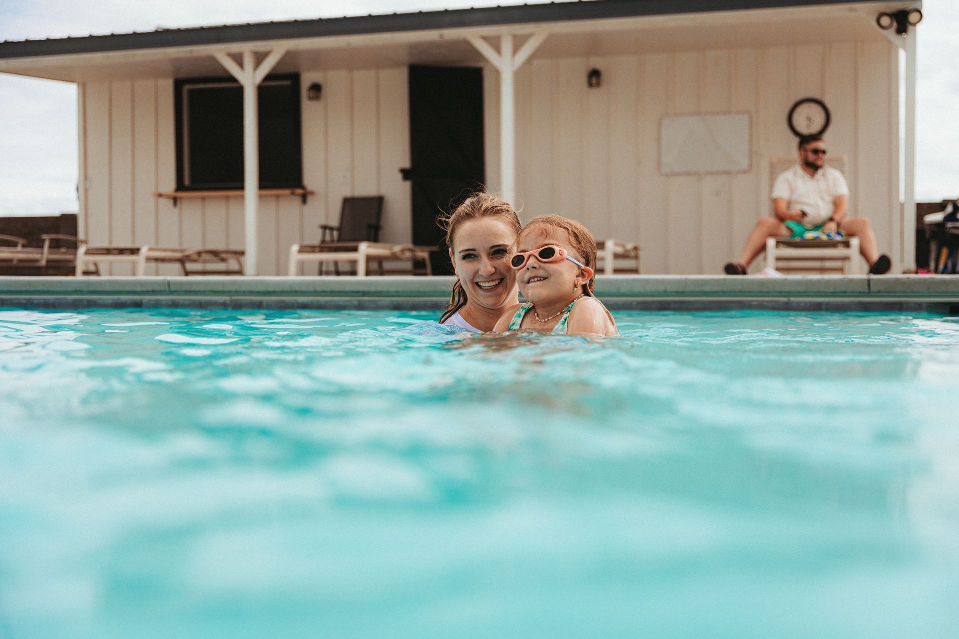 A woman and a child are swimming in a swimming pool.