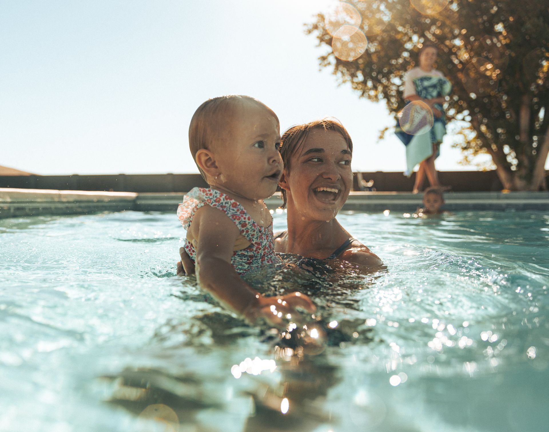 A woman is holding a baby in a swimming pool.
