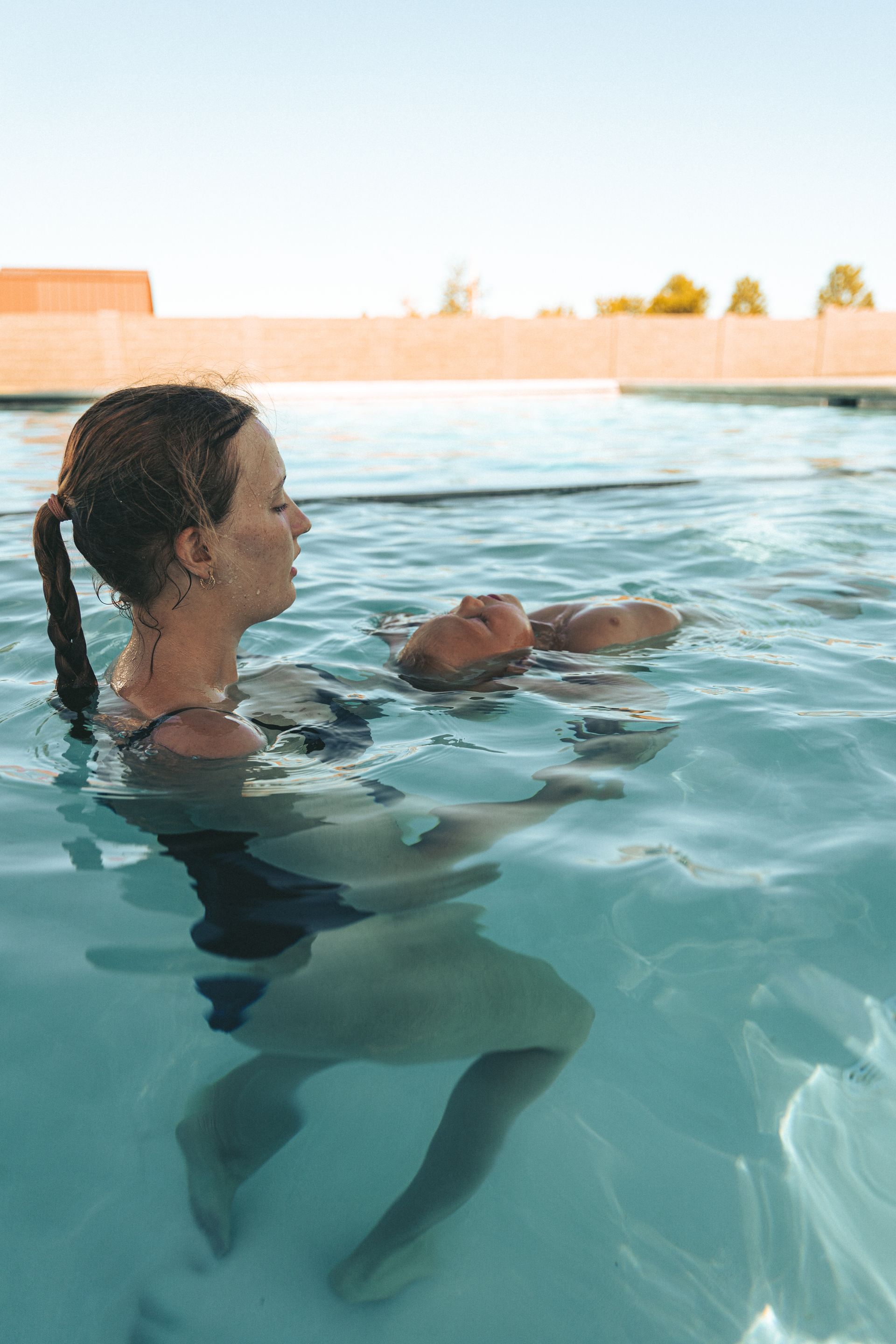 A woman is holding a baby in a swimming pool.