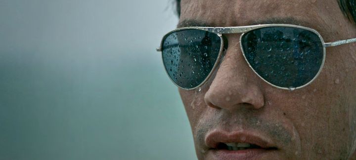 a close up of a man wearing sunglasses in the rain .