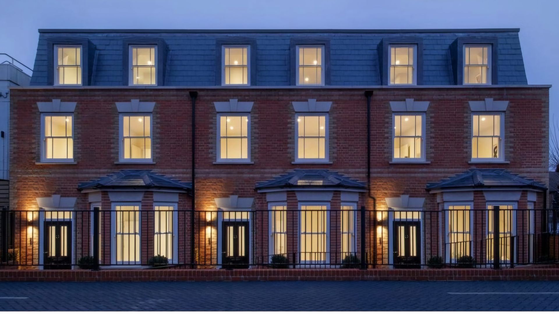 Brick row houses with lit windows at dusk.