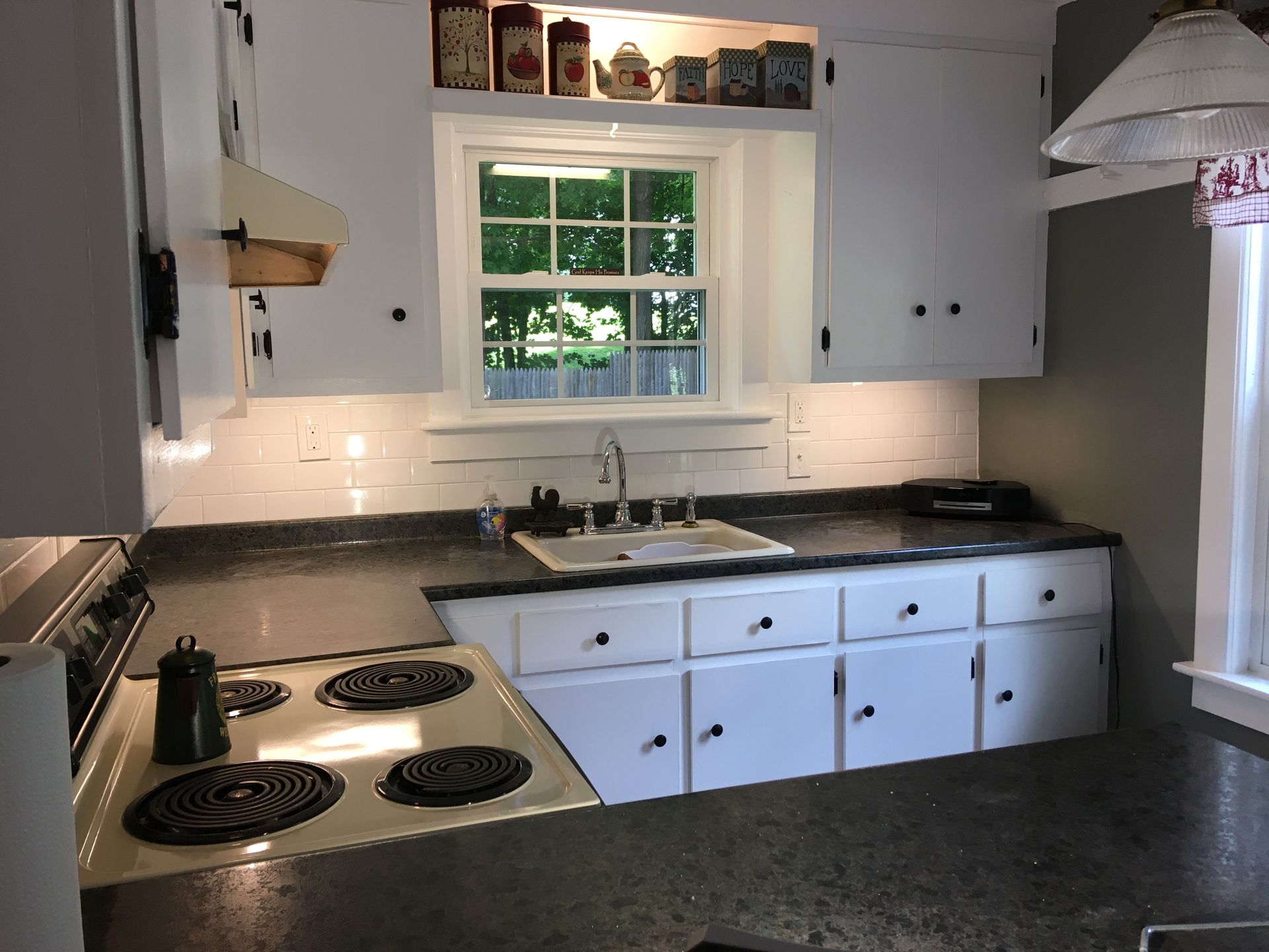 A kitchen with white cabinets and black counter tops