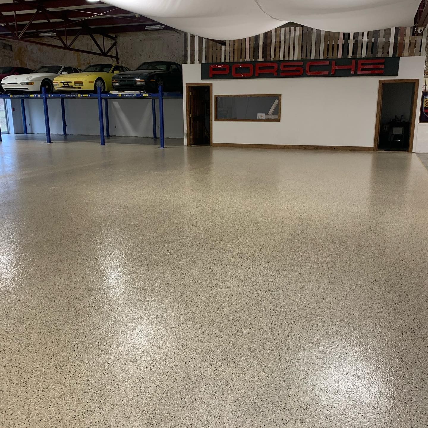 Garage with epoxy flooring, displaying Porsches on lifts and a