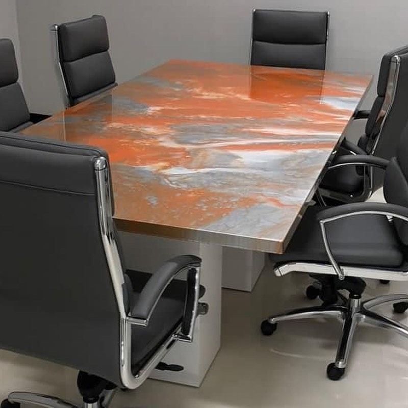 Conference table with orange and gray epoxy surface, surrounded by black chairs.