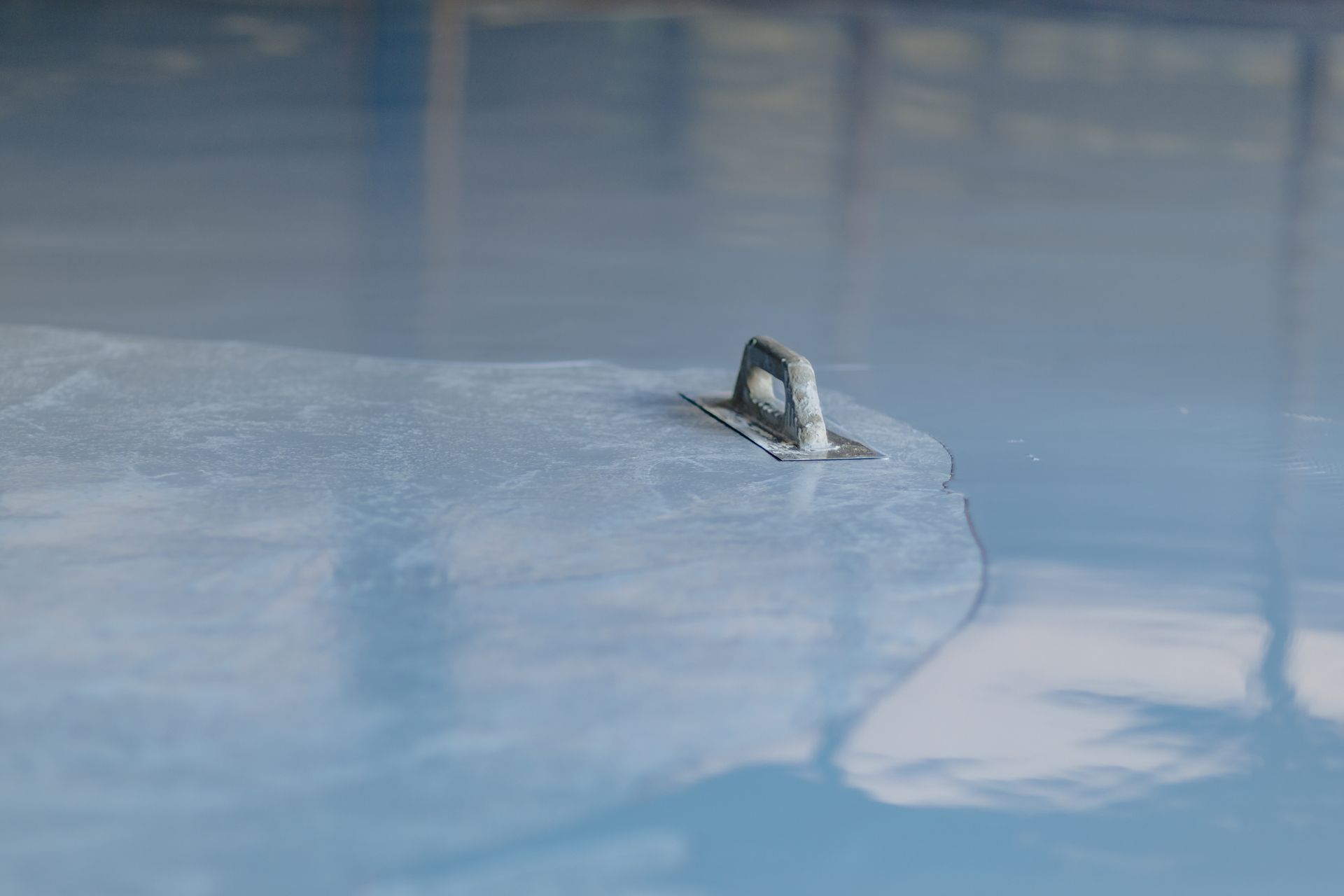 Metal anchor embedded in a smooth, blue-gray epoxy floor.