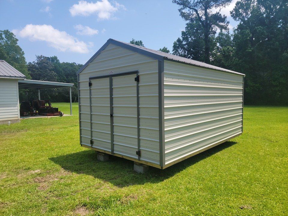 A row of sheds are sitting in a grassy field.