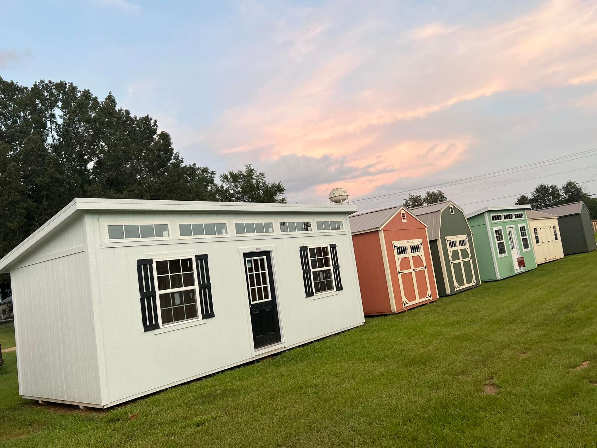 A row of sheds are lined up in a grassy field.