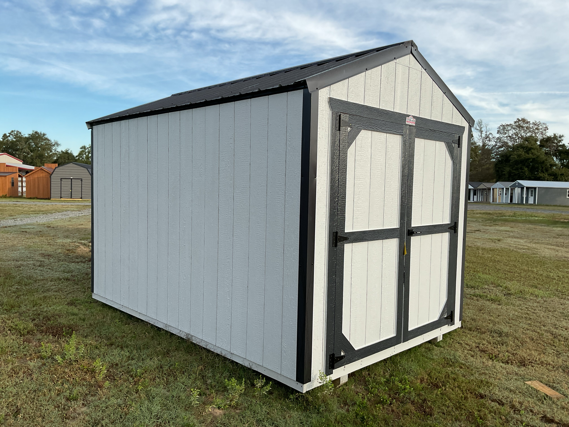A teal shed on a trailer, ready for transport, in a field at dusk.