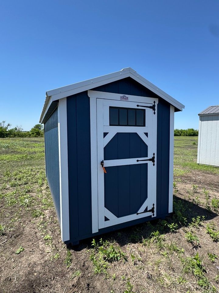 A small blue and white shed is sitting in the middle of a field.