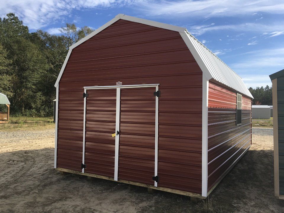 A red barn with white trim is sitting on top of a dirt field.