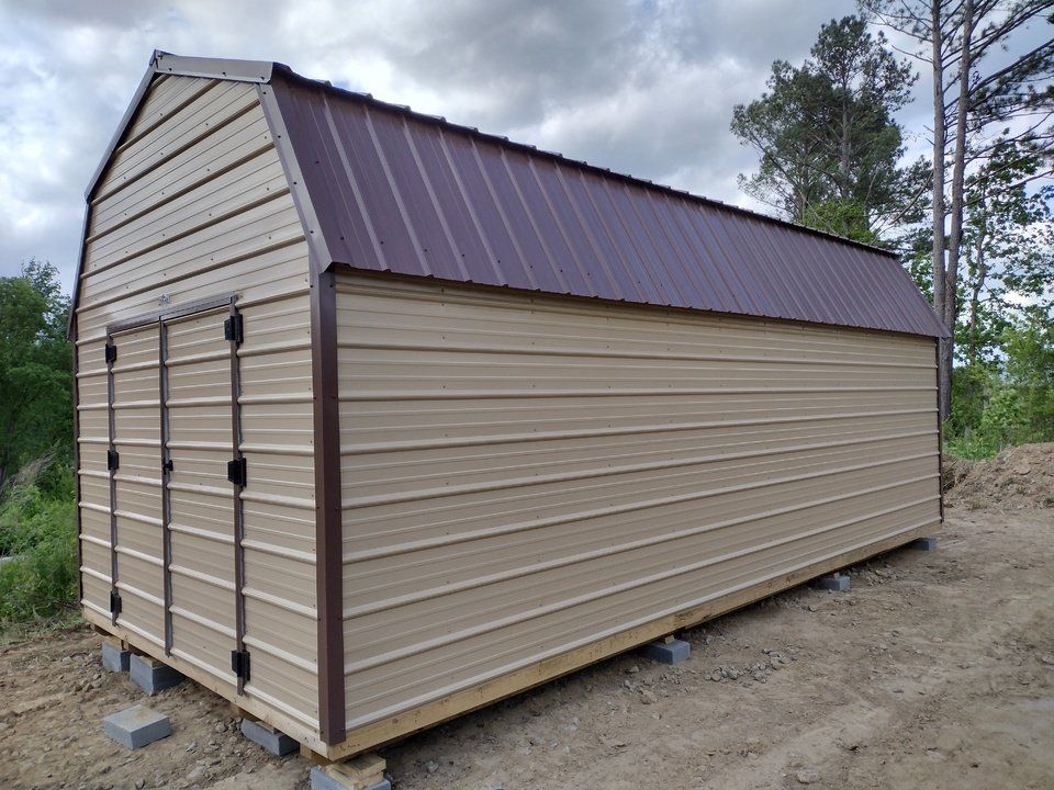 A shed is sitting in the middle of a lush green field.