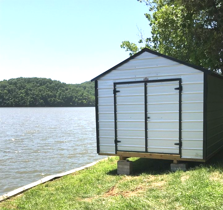 A small metal shed sits next to a body of water