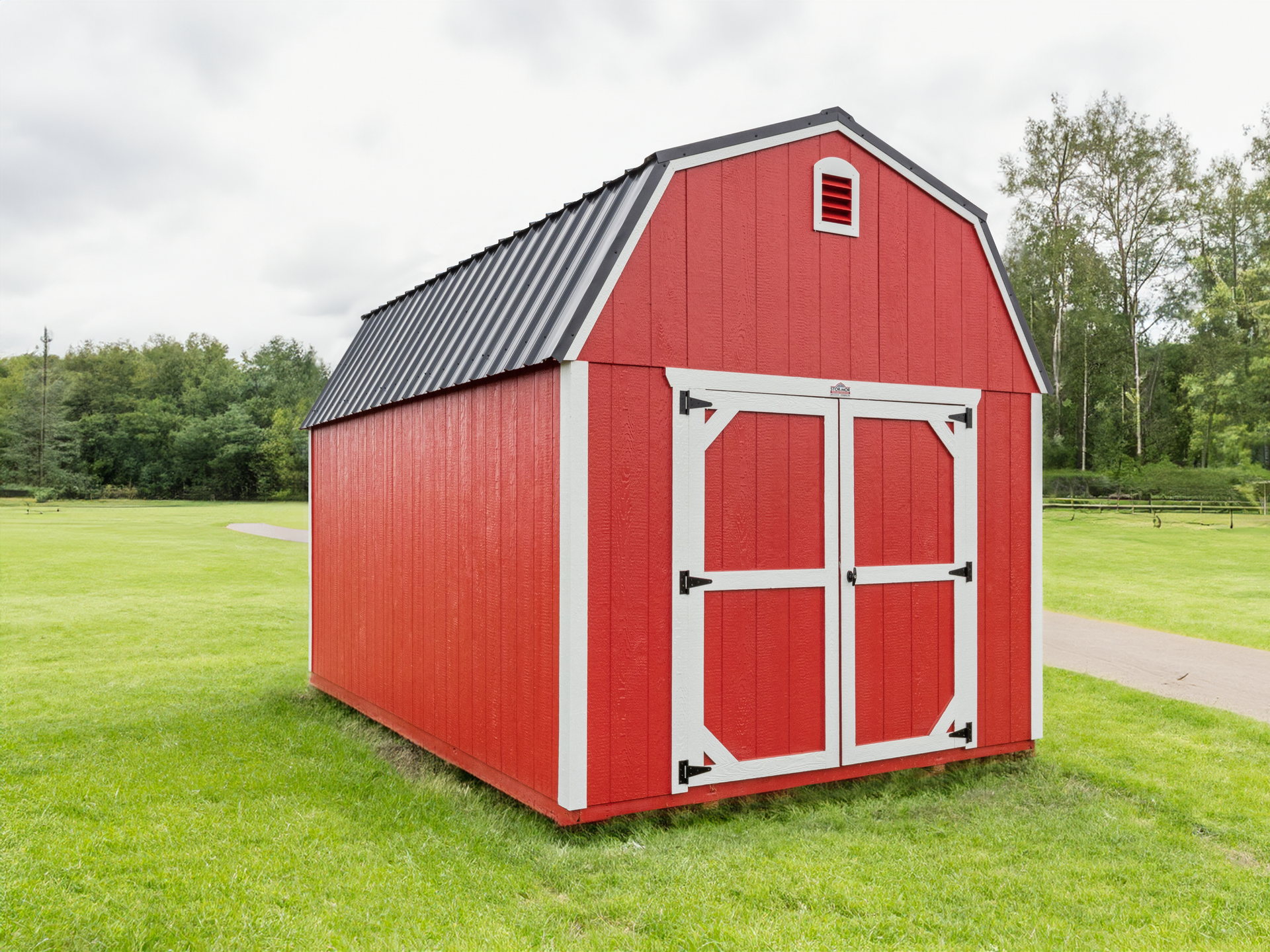 A red barn is sitting in the middle of a grassy field.