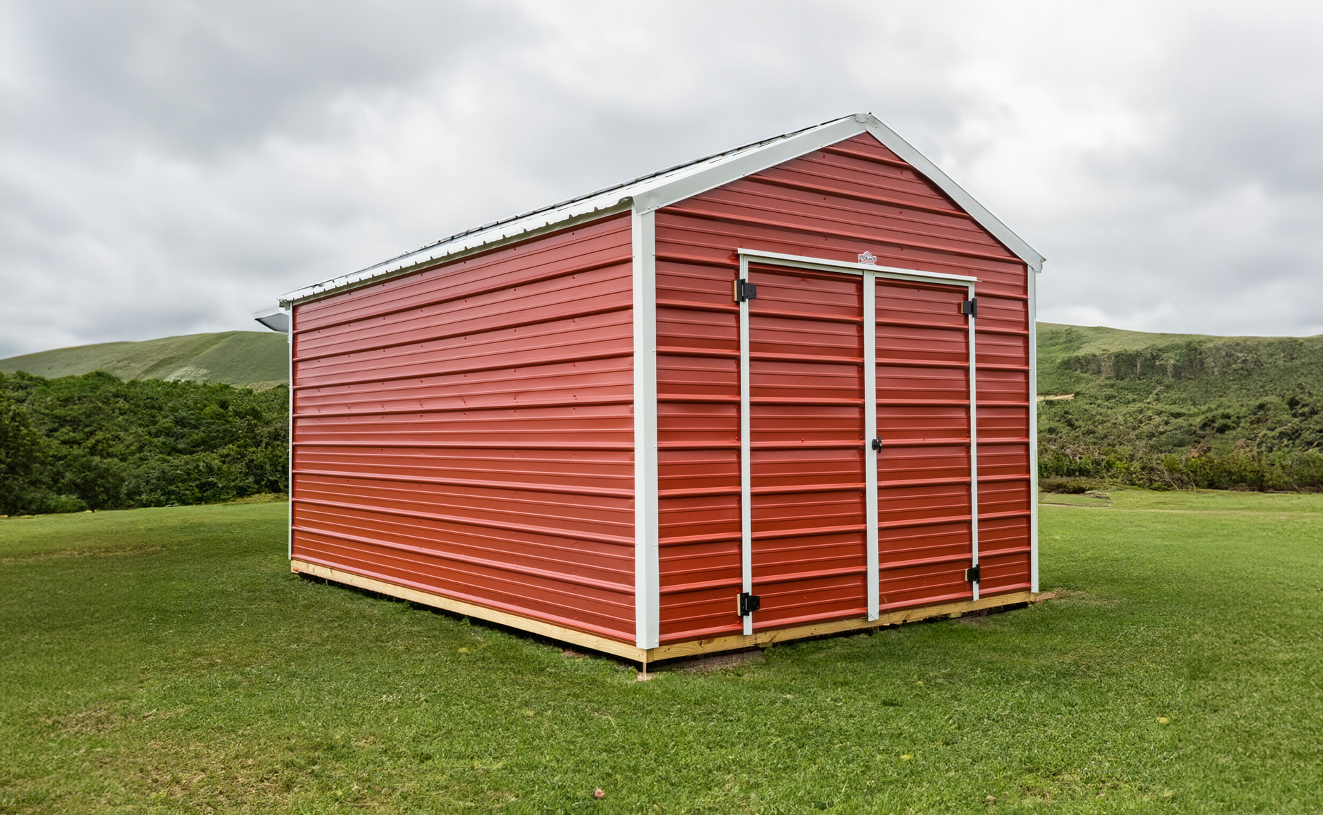 A red metal shed is sitting in the middle of a grassy field.