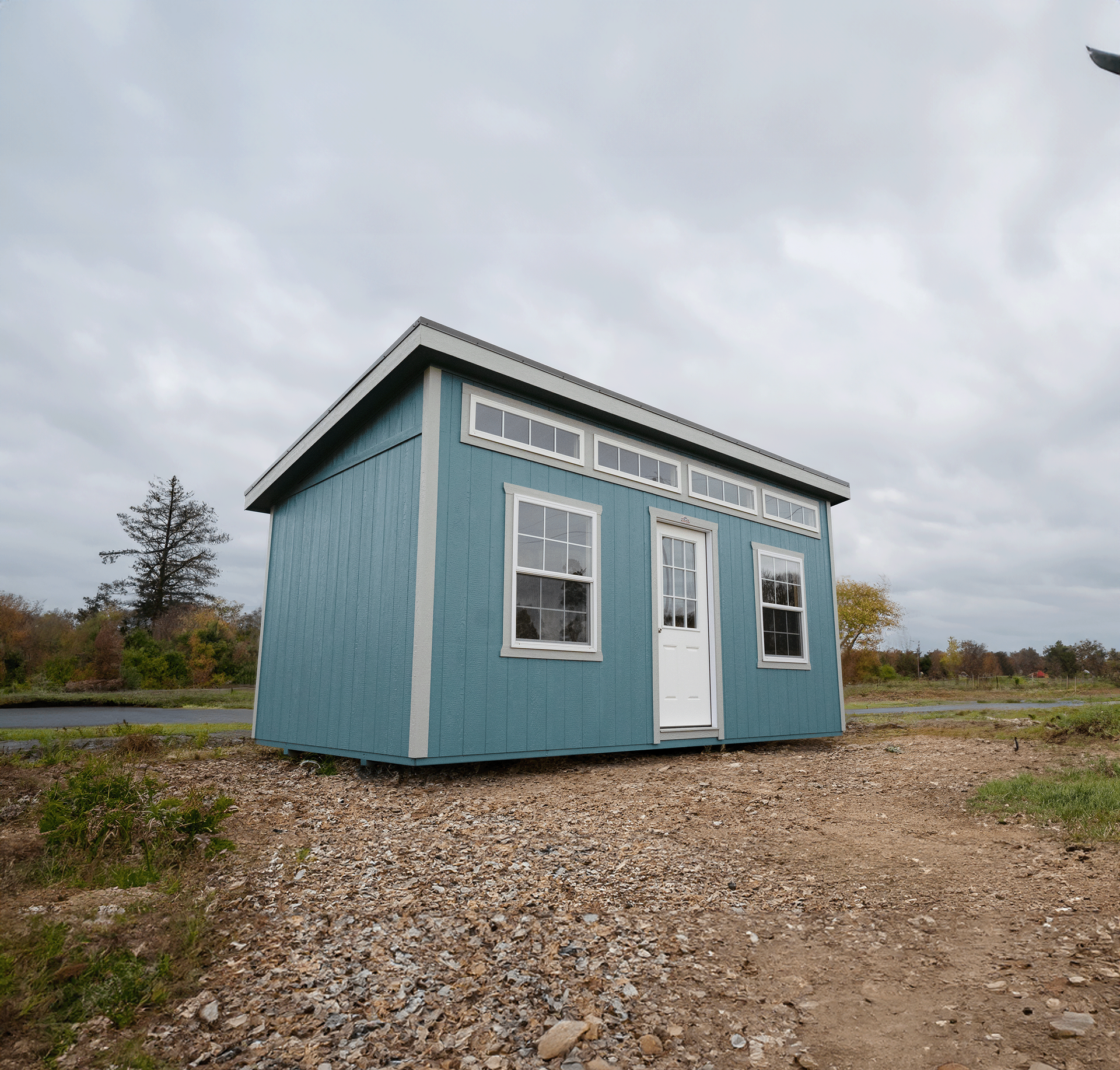 A small blue shed with a white door and windows