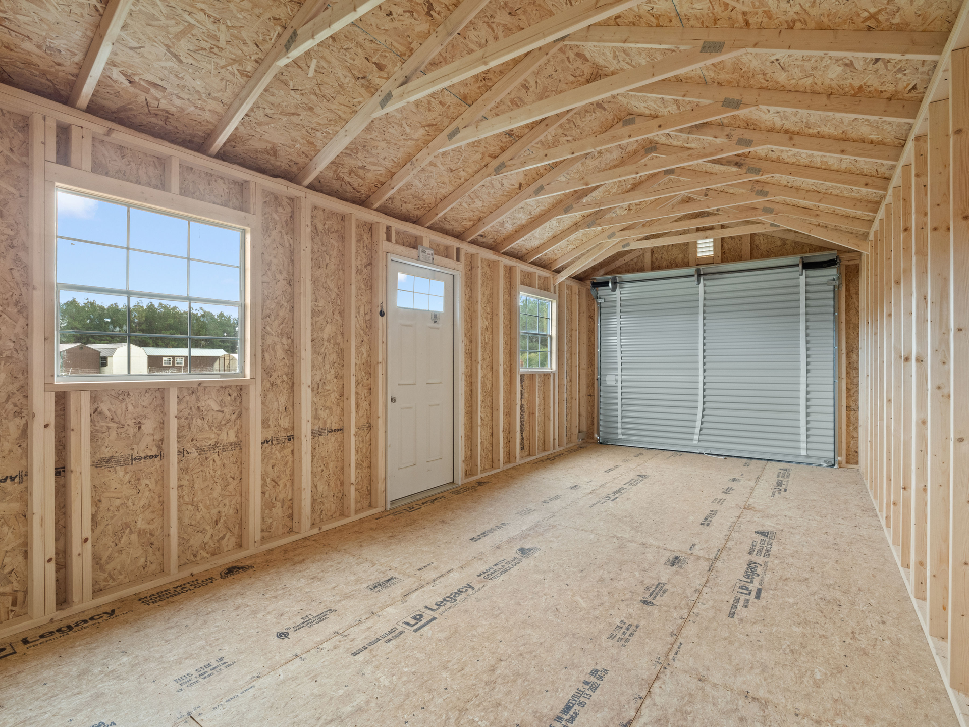 The inside of a portable wooden garage with a garage door and windows.
