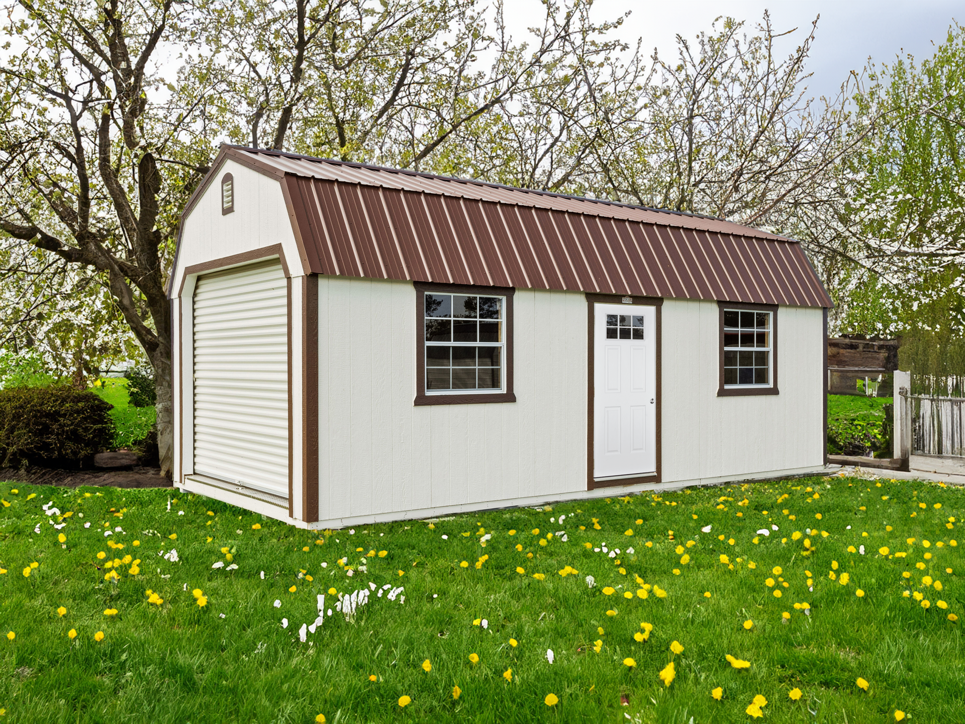 A white shed with a brown roof is sitting in the middle of a lush green field.