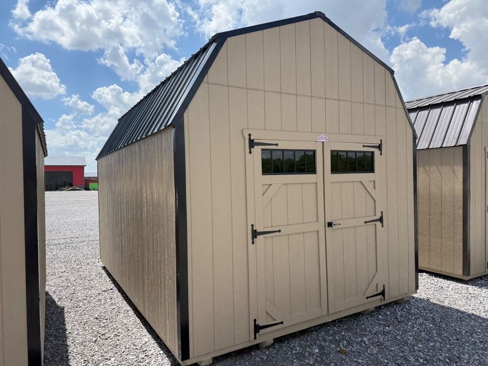 A small white shed is sitting in the middle of a dirt field.