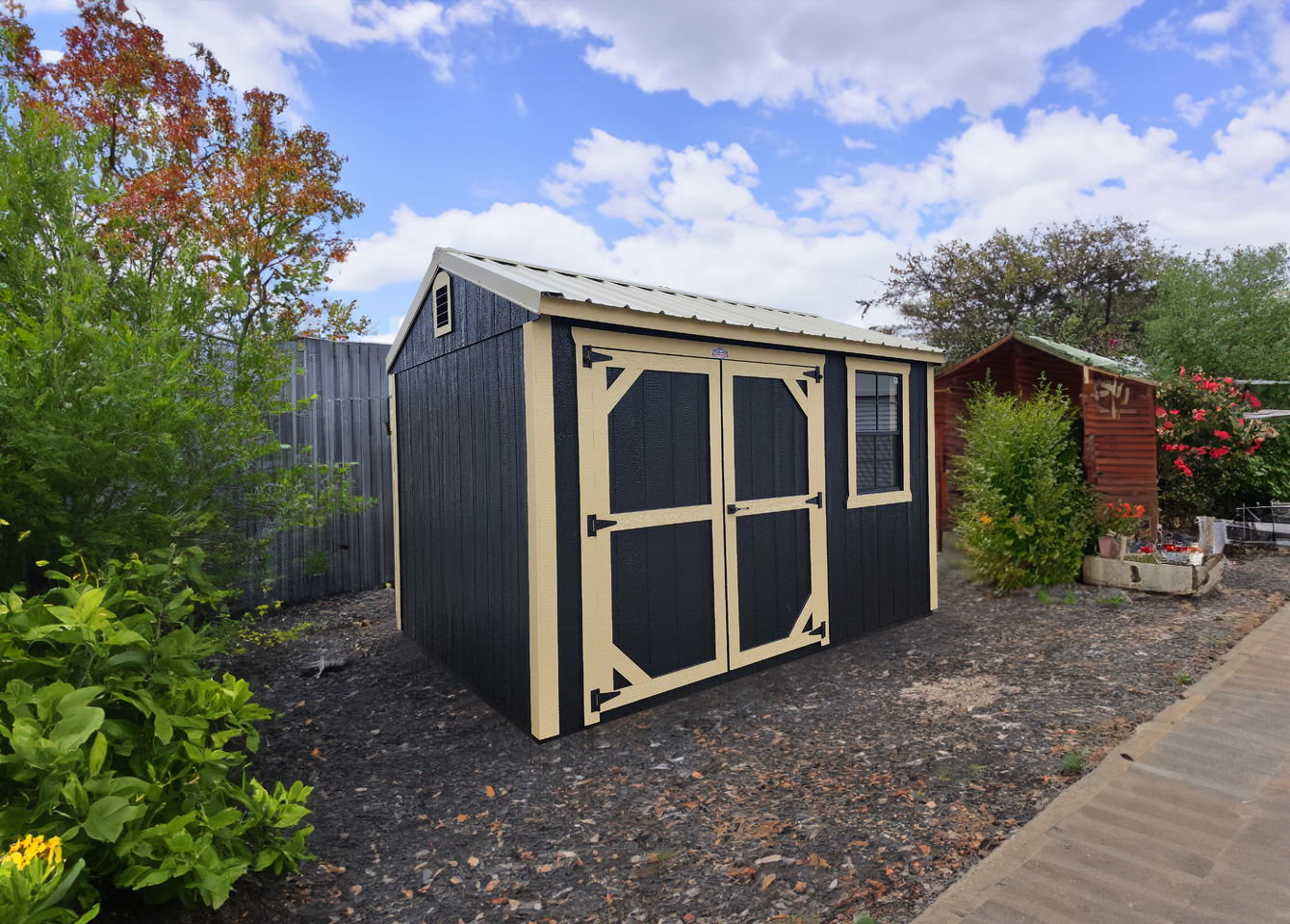A black shed sitting in a gravel yard.