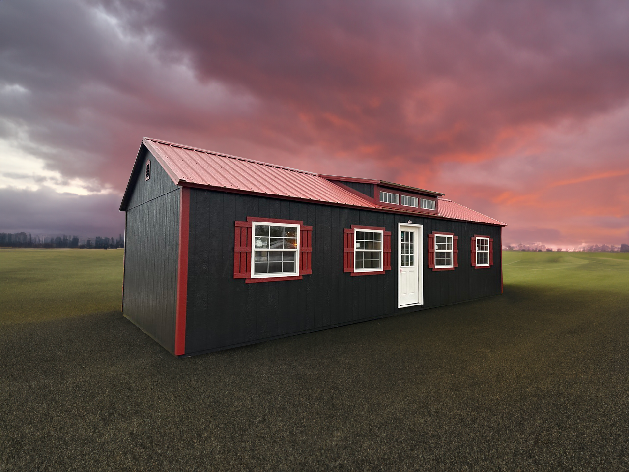 A black house with red shutters and a red roof is sitting in the middle of a field.
