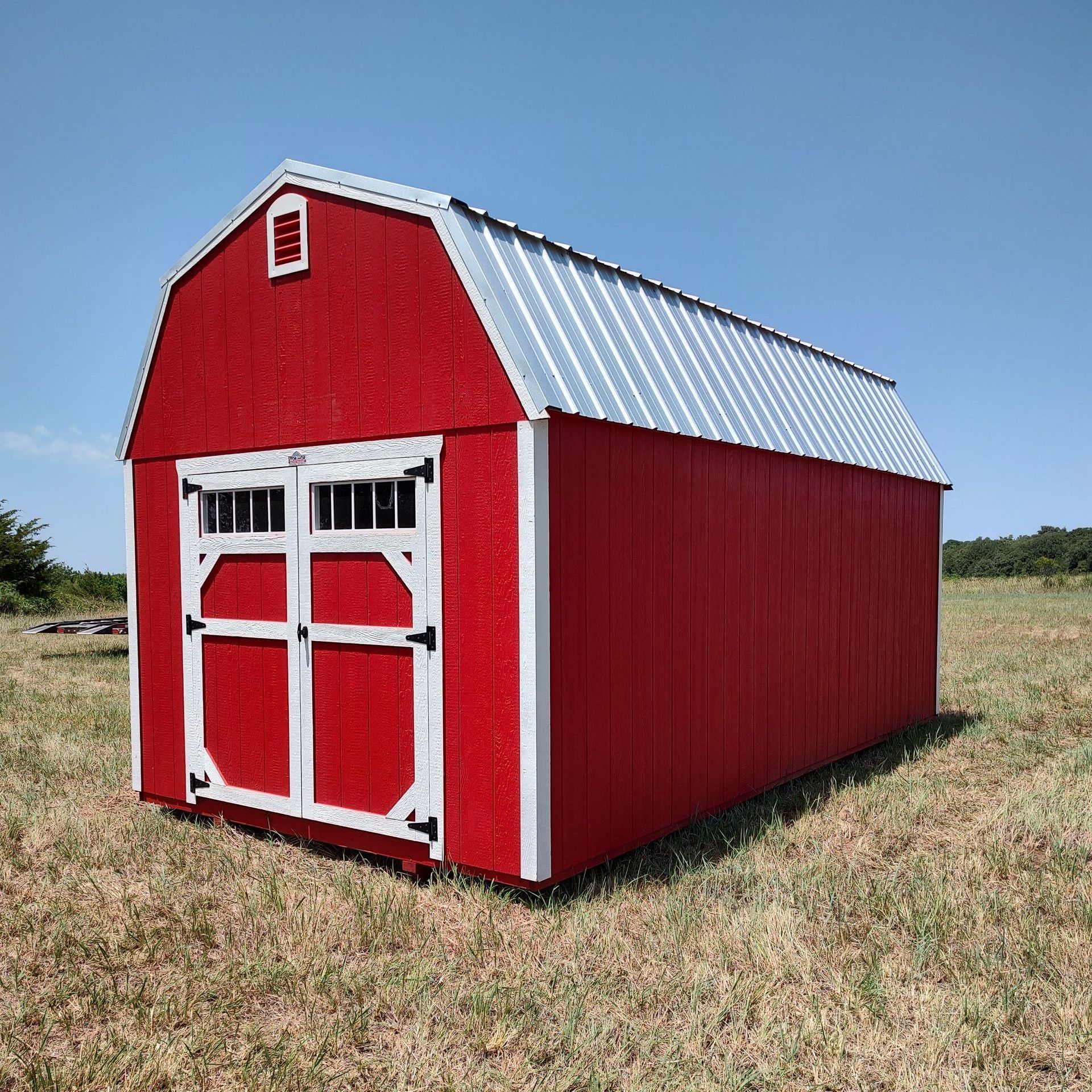 A red barn is sitting in the middle of a grassy field