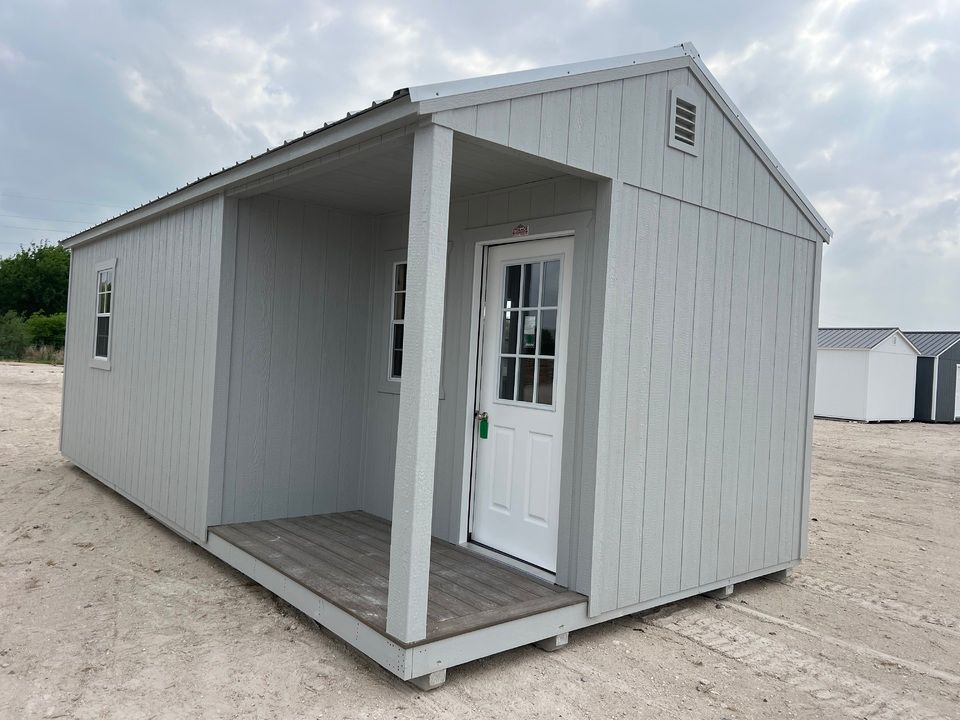 A small white shed with a porch and a door.