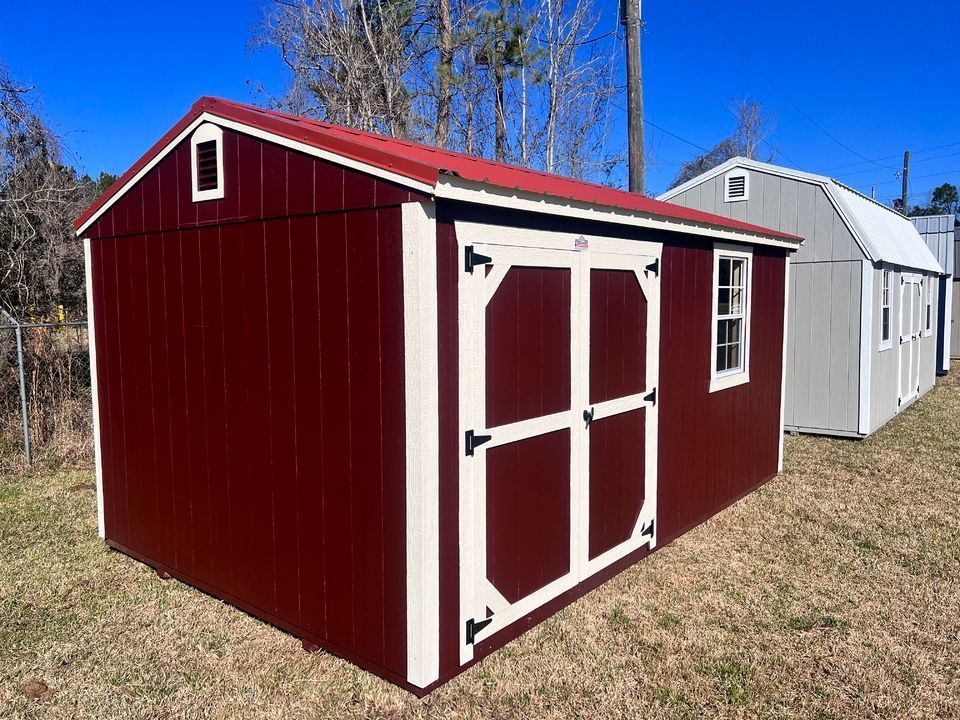 A red and white shed with a red roof is sitting in the grass.