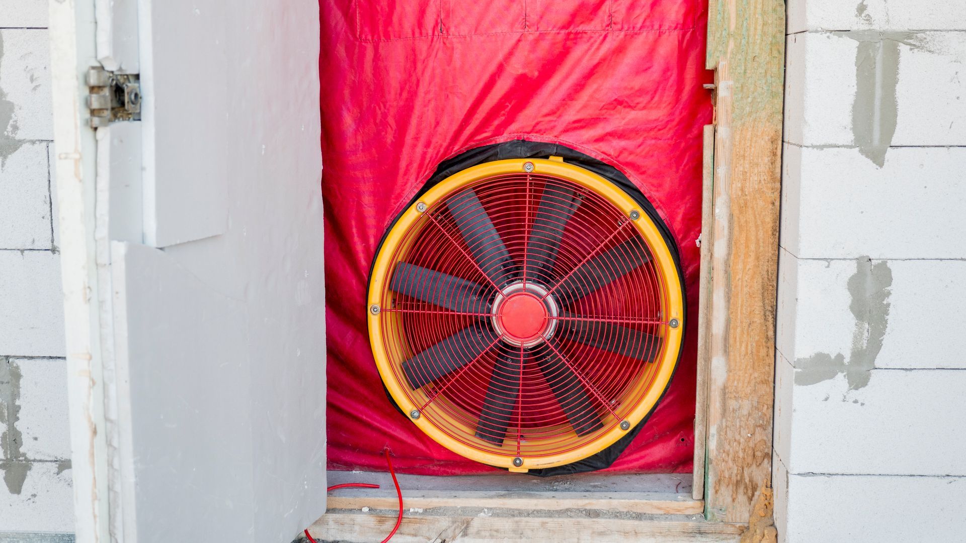 A red and yellow fan is sitting inside of a door.