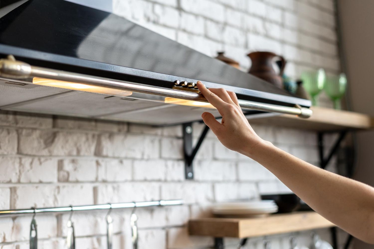 A person is adjusting a hood in a kitchen.