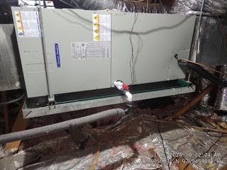 A large air conditioner is sitting in the attic of a house.