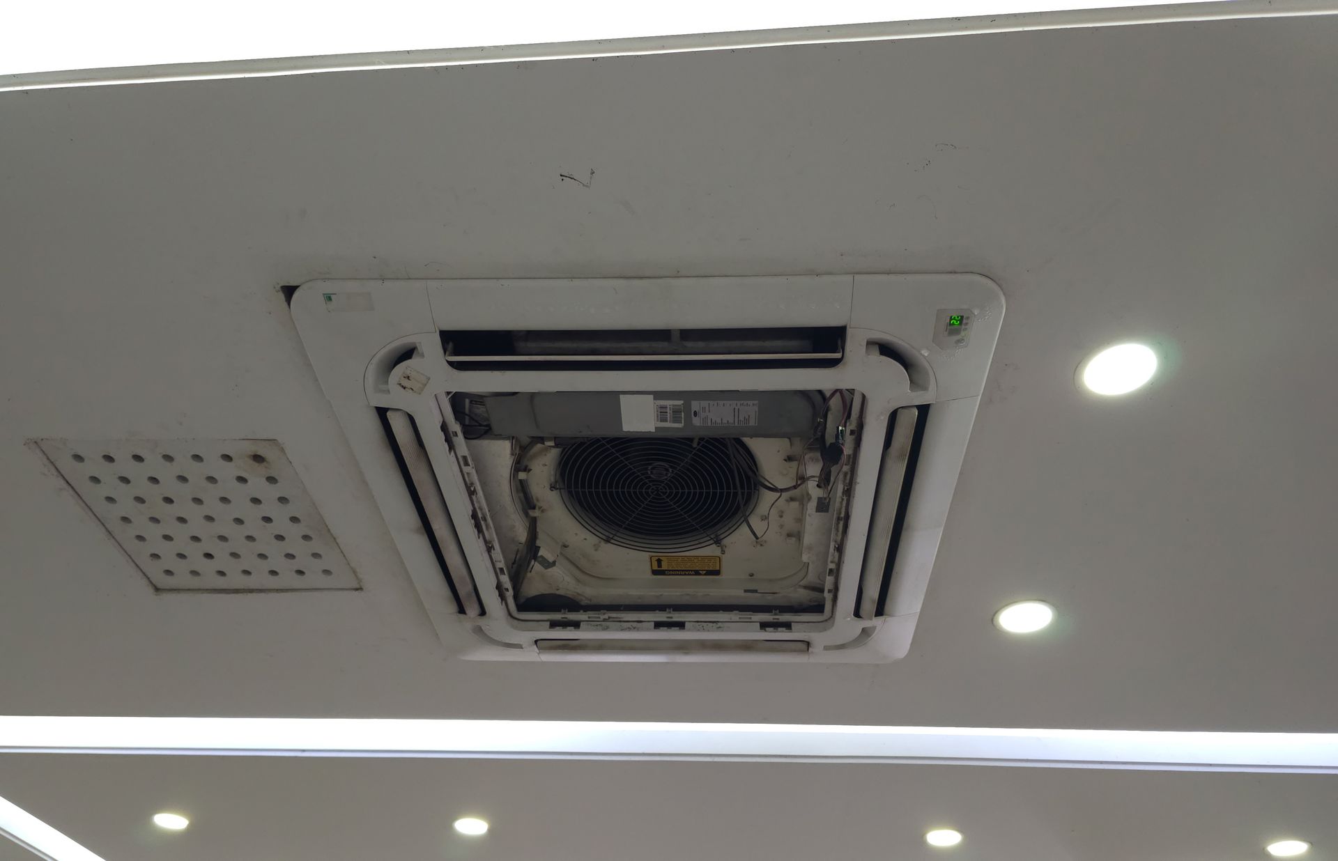Ceiling-mounted air conditioner with the front panel open, exposing the fan.