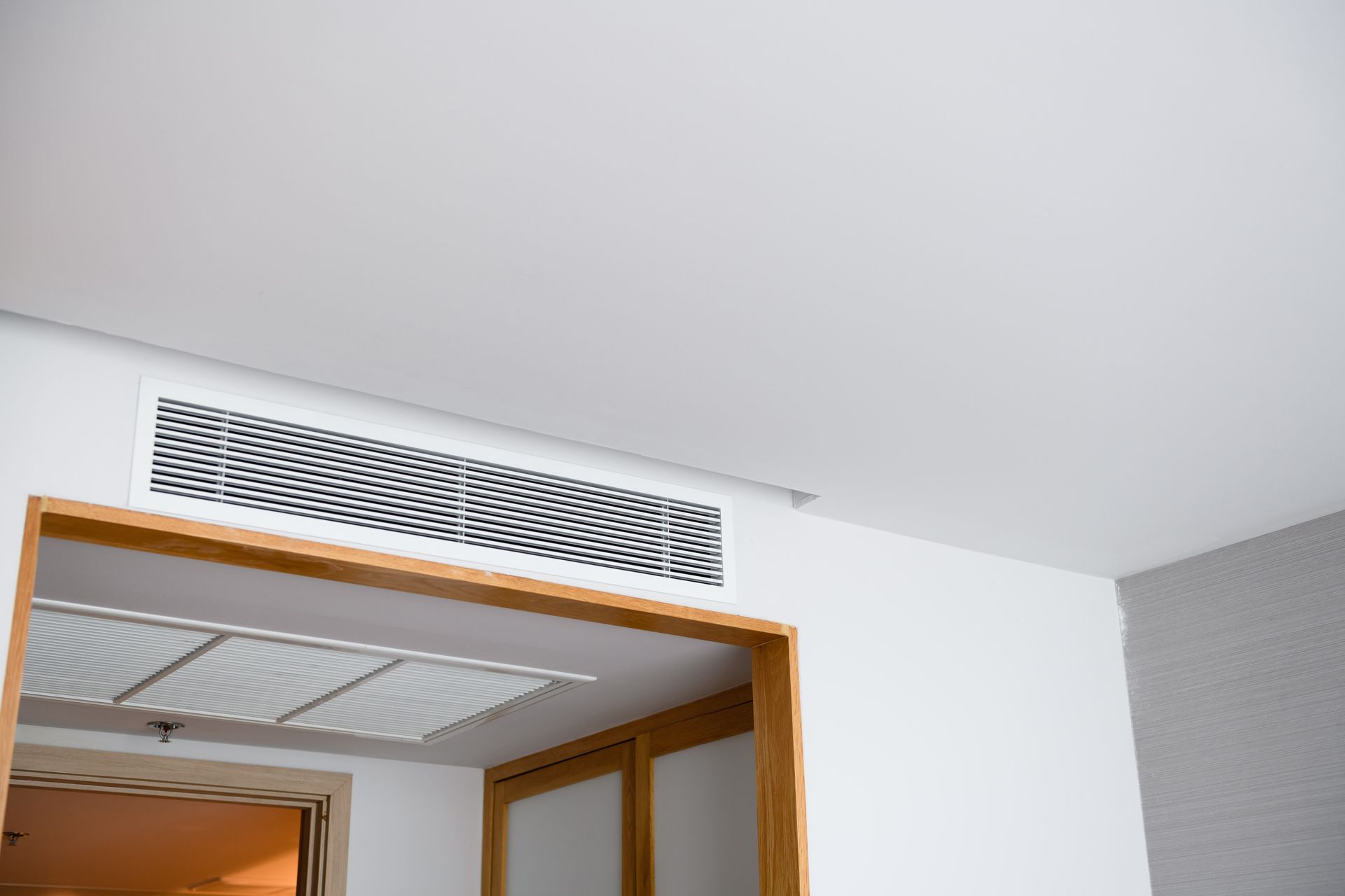 Ceiling air vent above a wooden doorway in a modern room