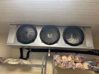 Three fans are hanging from the ceiling of a refrigerator.