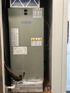 An air conditioner is sitting in a closet next to a door.