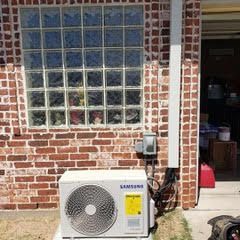 A samsung air conditioner is sitting on the side of a brick building.