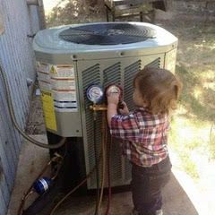 A little boy is working on an air conditioner outside.